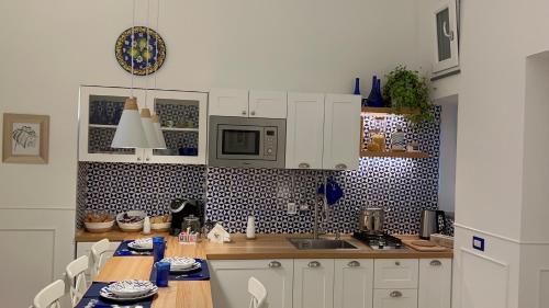 a kitchen with white cabinets and a table and a microwave at St. Vincent Apartment in Castellammare di Stabia