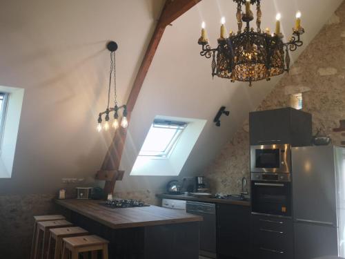 a kitchen with a chandelier and a kitchen with a refrigerator at La Longère du Val in Tauxigny