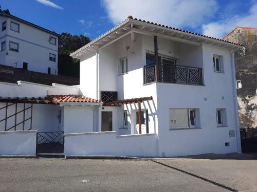 een wit huis met een balkon aan de zijkant bij Apartamentos Costa San Esteban in San Esteban de Pravia