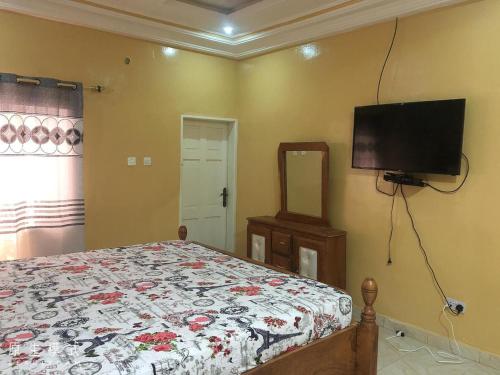 a bedroom with a bed and a flat screen tv at AwaMuuLamin MANNEH GUEST HOUSE in Abuko