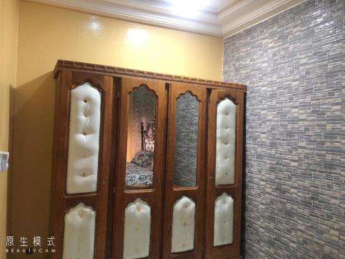 a wooden cabinet in a room next to a brick wall at AwaMuuLamin MANNEH GUEST HOUSE in Abuko