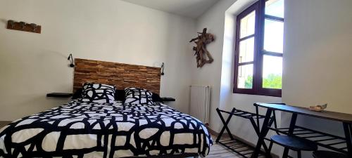 Schlafzimmer mit einem Bett, einem Tisch und einem Fenster in der Unterkunft Gîte climatisé "Baugallo Acampadis" in Saint-Montan