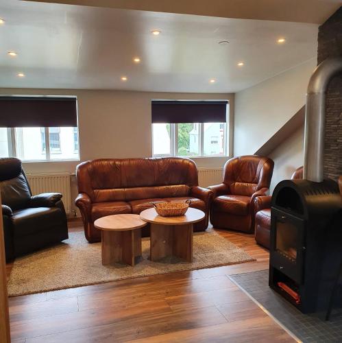 a living room with leather furniture and a wood stove at E18 Apartments in Akureyri