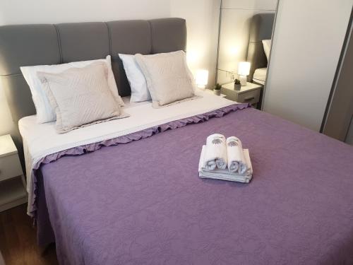 um quarto com uma cama roxa com dois pares de chinelos em Lavanda 2 em Split