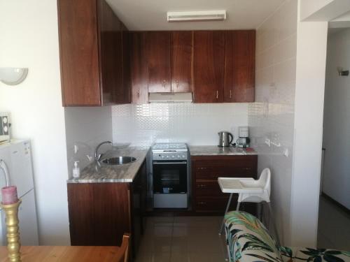 a small kitchen with wooden cabinets and a sink at Apartamento Casa hollanda in Mindelo