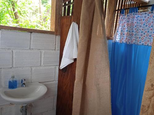 a bathroom with a sink and a blue shower curtain at Finca Ecoturistica LOS JAGUEYES in Baraya