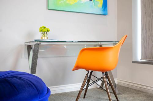 an orange chair sitting in front of a glass desk at Retro Suites Hotel in Chatham