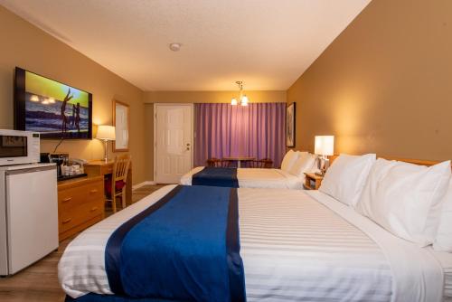 a hotel room with two beds and a television at Ocean Crest Motel in Qualicum Beach