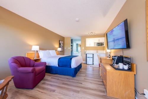 a hotel room with a bed and a tv at Ocean Crest Motel in Qualicum Beach