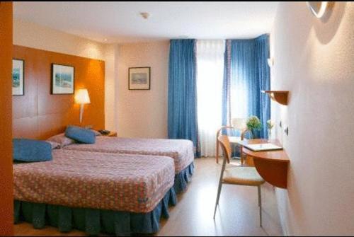 Cette chambre comprend deux lits et un bureau. dans l'établissement Hotel Restaurante Salvadora, à Villena