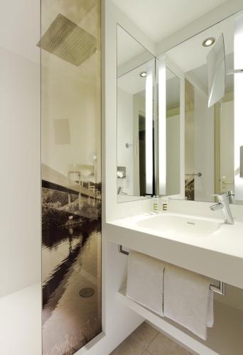a white bathroom with a sink and a mirror at Mercure Cergy Pontoise Centre in Cergy