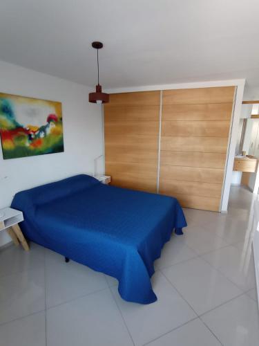 a bedroom with a blue bed and a wooden door at Departamentos Kairos H in Mendoza
