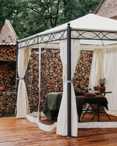 a tent with a table in front of a pile of logs at Rubeni in Stāķi