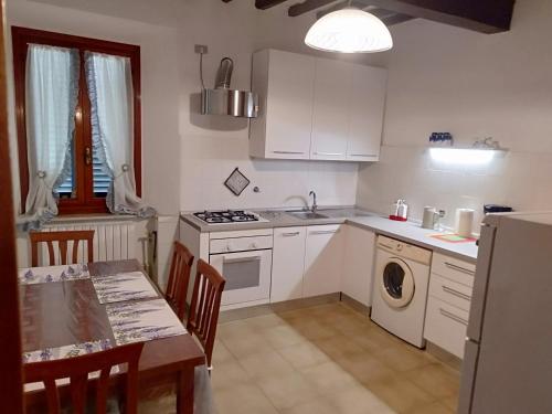 a kitchen with white cabinets and a table and a table and a sink at La casa di Elisa in Vinci