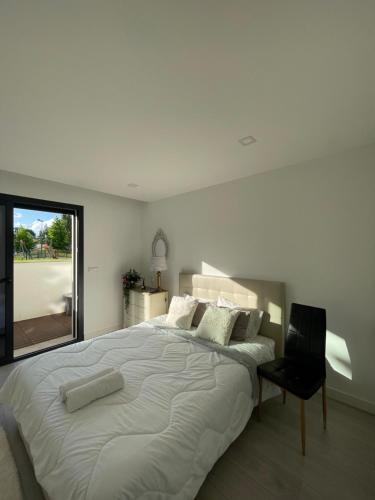 a white bedroom with a large bed and a chair at Quarto Privado em Alojamento Local perto do Rio Vez em Arcos de Valdevez in Arcos de Valdevez