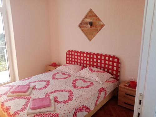 a bedroom with a bed with a red headboard at Apartmani Bosco in Tivat