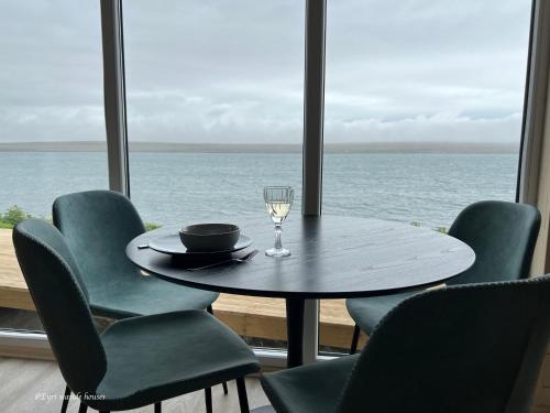 a table and chairs with a glass of wine and the ocean at Eyri Seaside Houses in Hvammstangi