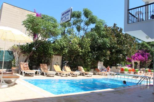 a swimming pool with chairs and a person in the water at Britannia Hotel Village in Kemer