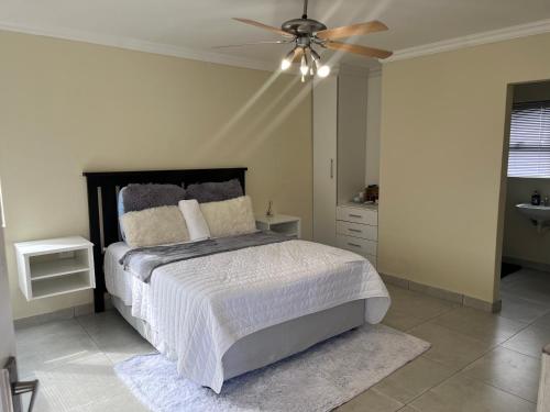 Un dormitorio con una cama y un ventilador de techo. en Mafini Villa, en Centurion