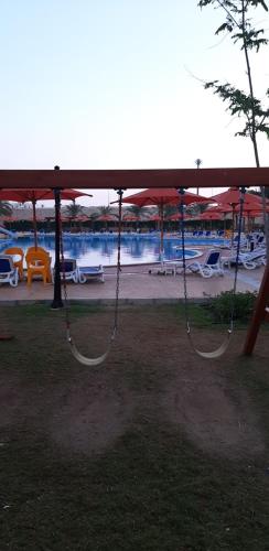 a swing in a park with a view of a beach at Sea view apartment, Aqua View Resort, North coast in El Alamein