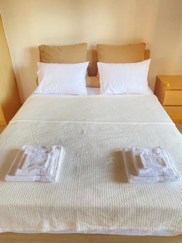 a bed with white sheets and two towels on it at Seaside one-bedroom on Chalkis in Chalkida