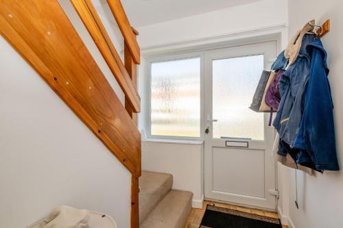 a staircase leading to a door with a coat hanging on it at 38 Dale End in Brancaster