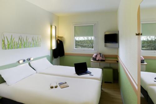 a hotel room with a bed with a laptop on it at Ibis Budget Montelimar in Montélimar