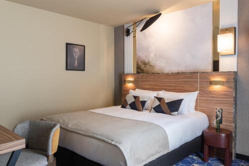 a hotel room with a large bed and a chair at Hotel Le Rocroy in Paris