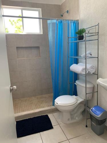 a bathroom with a toilet and a blue shower curtain at Departamento 2 habitaciones vista a la alberca Sky by EITA in Cancún