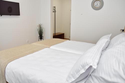 a white bed with white sheets and a clock on the wall at Hotel Premium in Jajce