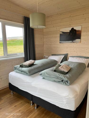 two beds in a bedroom with a large window at Eyri Seaside Houses in Hvammstangi