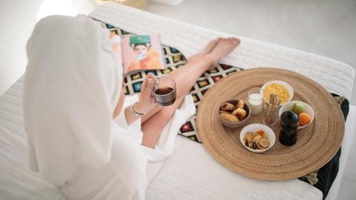 a woman laying on a bed with a tray of food at Irida Vacation suites in Kastraki Naxou