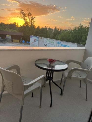 een tafel en stoelen op een balkon met uitzicht op de zonsondergang bij Apartments MASIMO in Donji Štoj