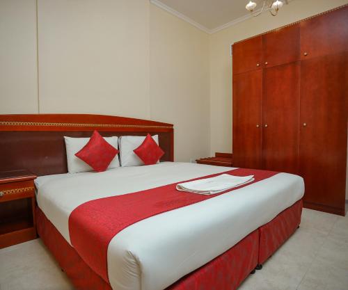 a bedroom with a large bed with red and white pillows at Al Sharq Hotel Suites - BAITHANS in Sharjah