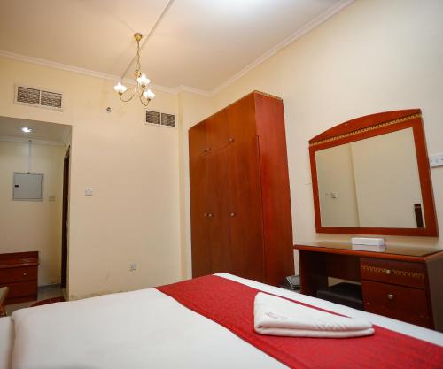 a bedroom with a bed and a dresser and a mirror at Al Sharq Hotels Suites in Sharjah