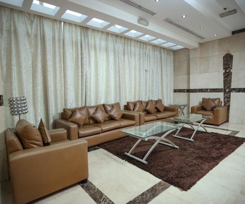 a living room with brown couches and a glass table at Al Sharq Hotels Suites in Sharjah