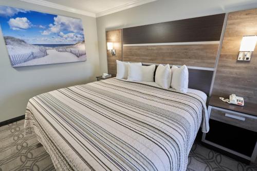 a hotel room with a large bed with white pillows at Ambassador Inn and Suites in South Yarmouth