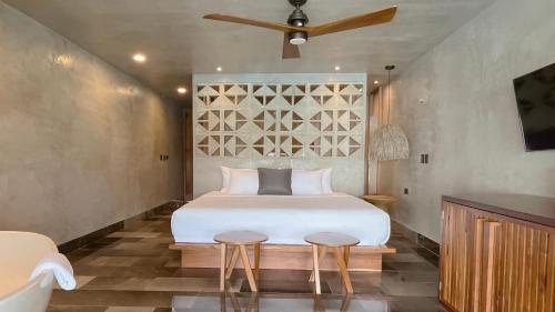 a bedroom with a bed and two stools at Hotel Amainah Bacalar Adults Only in Bacalar