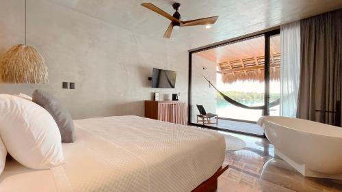 a bedroom with a bed and a tub and a window at Hotel Amainah Bacalar Adults Only in Bacalar