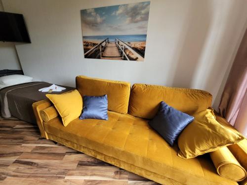 a living room with a yellow couch and a bed at Dom Przy Plaży in Sarbinowo