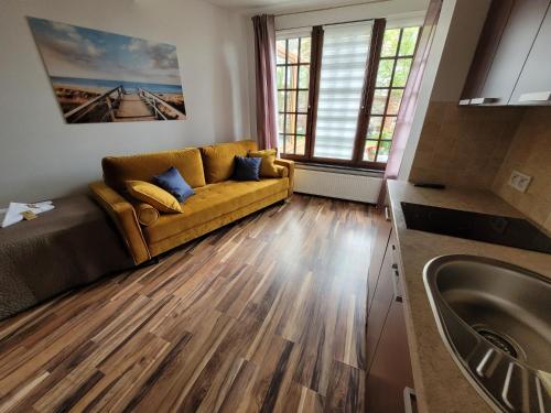 a living room with a couch and wooden floors at Dom Przy Plaży in Sarbinowo