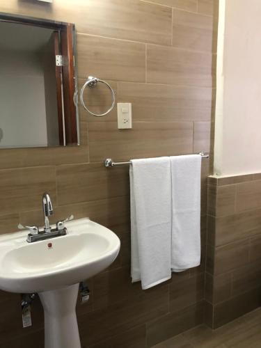 a bathroom with a sink and a mirror and towels at Hotel Lorena in Los Mochis