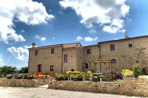 a large stone building with flowers in front of it at Agriturismo Fonte Belvedere in Collesalvetti