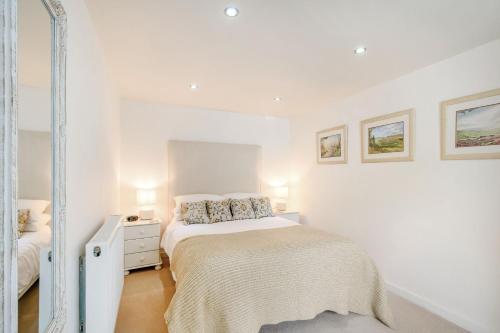 a white bedroom with a bed and a mirror at Cow Byre Cottage in Snainton