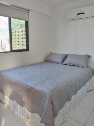 uma cama grande num quarto branco com uma janela em Apartamento em Boa Viagem em Recife