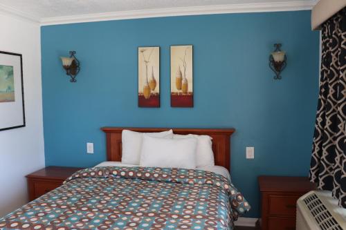 a blue bedroom with a bed and three pictures on the wall at El Dorado Motel in Gardena
