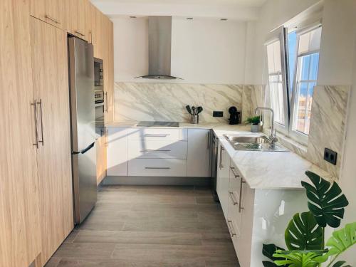 een keuken met witte kasten en een roestvrijstalen koelkast bij House Sofi , Morro Jable Ftvra. Canary Islands. in Morro del Jable