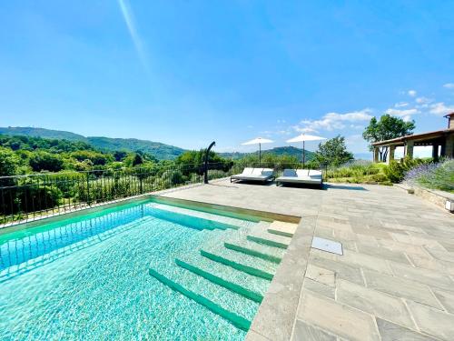 a swimming pool with two lounge chairs next to a house at Villa Podere Del Grasso in Castel del Piano