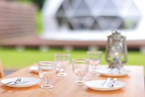 a wooden table with plates and glasses on it at Glamping Resort Varie in Fujikawaguchiko