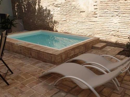 a swimming pool with two lounge chairs next to it at Belvilla by OYO Casa Palacio de la Carrera in Fuentes de Andalucía